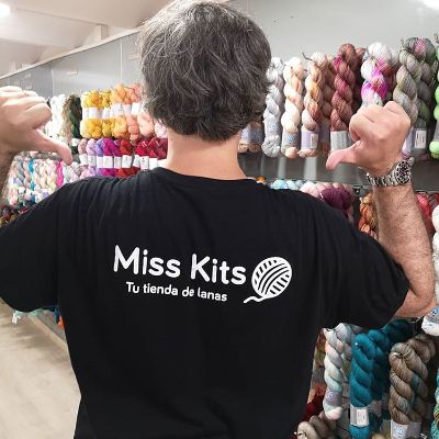 A boy with a t-shirt with Miss Kits logo and the tagline Your yarn shop, in Spanish